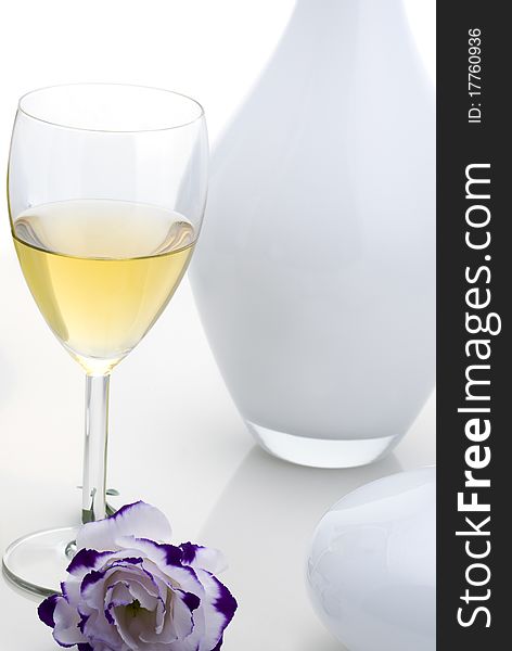 Glass of white wine with flower on white background.