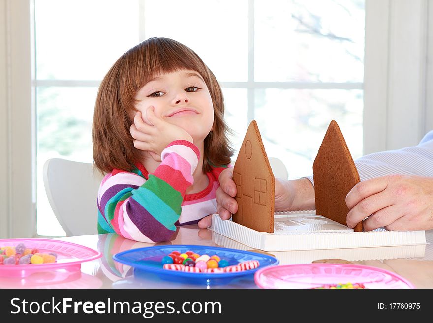 Little girl assembling and decorating gingerbread house for Christmas. Little girl assembling and decorating gingerbread house for Christmas