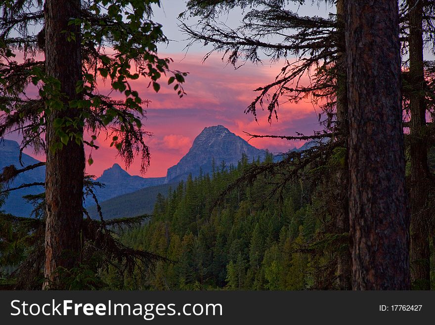Fiery red sunset behind the mountains seen thru the forest. Fiery red sunset behind the mountains seen thru the forest