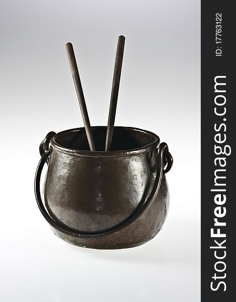 Old copper pot with two chopsticks on white. Old copper pot with two chopsticks on white