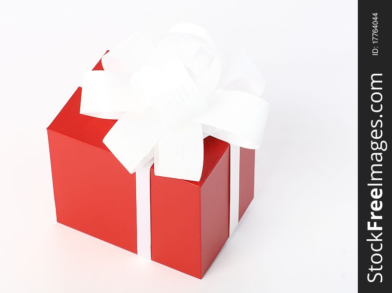 Close-up of a red gift box with white bow on neutral background