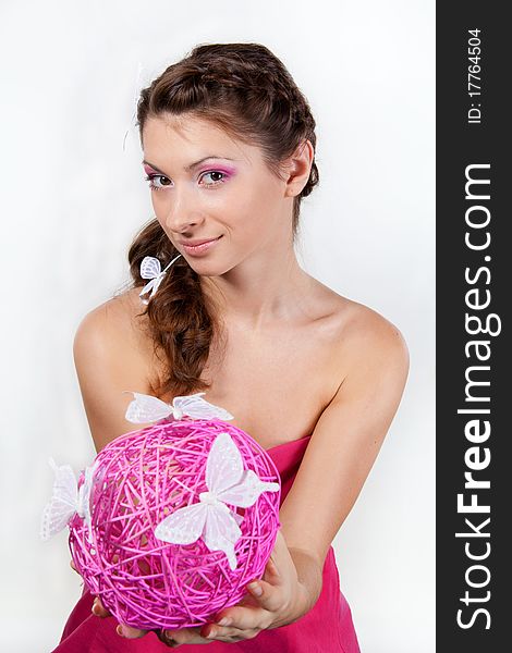 Portrait of young smiling woman with butterflies in her hair holding a pink sphere in her hands. Portrait of young smiling woman with butterflies in her hair holding a pink sphere in her hands