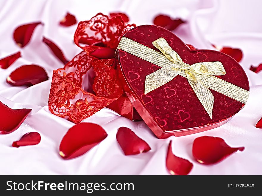 On a pink background gift box heart in the form of women's underwear, the background scattered rose petals. On a pink background gift box heart in the form of women's underwear, the background scattered rose petals.
