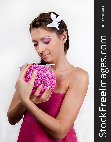 Young woman with butterflies in her hair and pink make-up looking on the sphere in her hands. Young woman with butterflies in her hair and pink make-up looking on the sphere in her hands