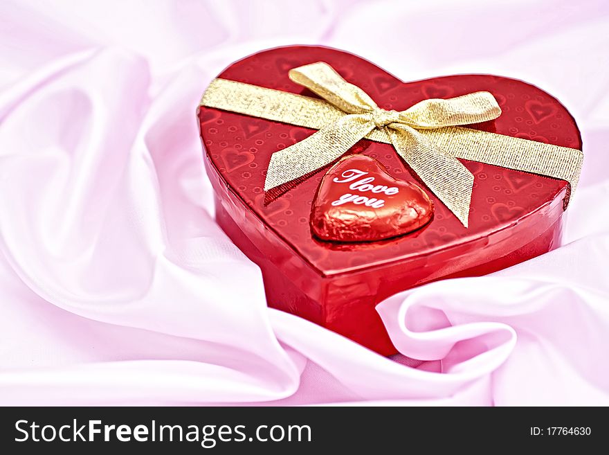 Pink bedding, gift box heart-shaped chocolate candy with the words I Love You. Surprise to the woman. Pink bedding, gift box heart-shaped chocolate candy with the words I Love You. Surprise to the woman.