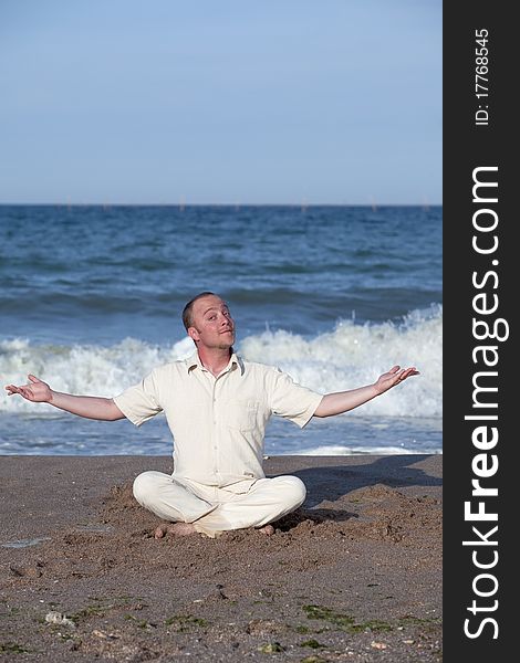 Young businessman doing yoga on a beach