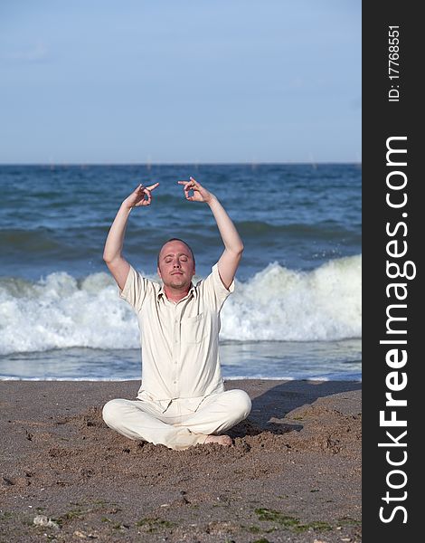 Young businessman doing yoga on a beautiful beach. Young businessman doing yoga on a beautiful beach