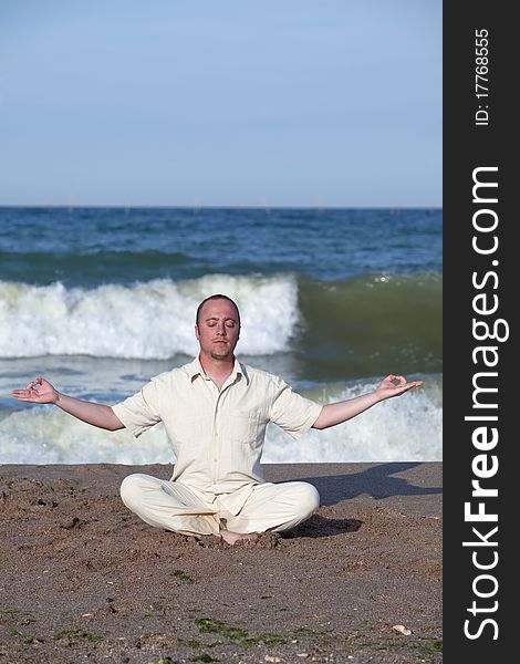 Young businessman doing yoga on a beach