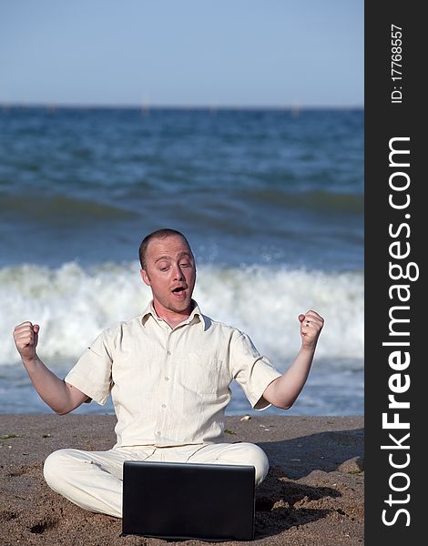 Young businessman at the beach with his laptop happy about success. Young businessman at the beach with his laptop happy about success