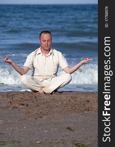 Young businessman doing yoga on a beach