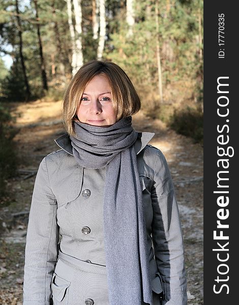 Woman wearing grey coat and scarf on a walk in the forest. Woman wearing grey coat and scarf on a walk in the forest.