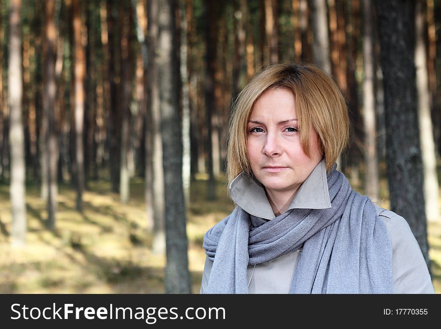 Woman wearing grey coat and scarf on a walk in the forest - portrait. Woman wearing grey coat and scarf on a walk in the forest - portrait.