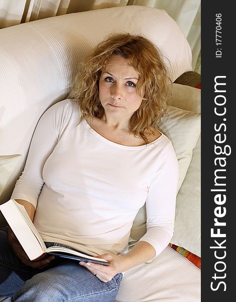 Young woman reading a book on a bright sofa. Young woman reading a book on a bright sofa.