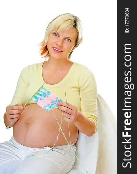Young pregnant woman knits cloth for her baby. Young pregnant woman knits cloth for her baby