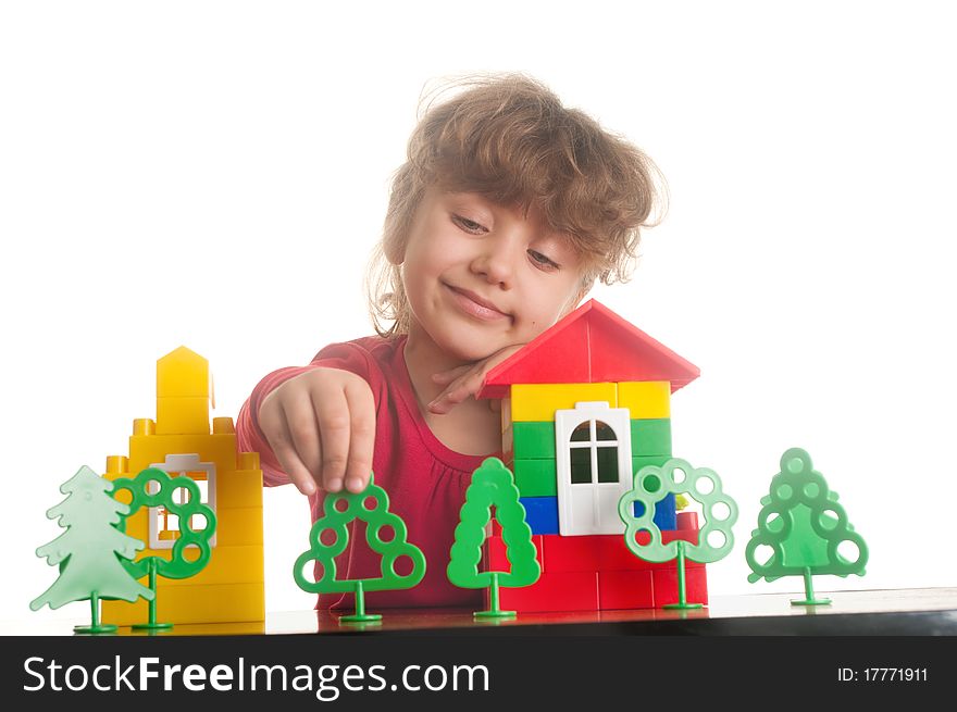 Cute little girl is constructing a house using building blocks