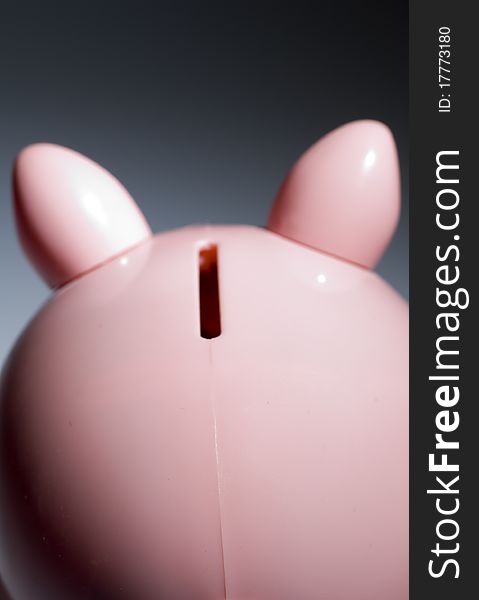 Back of Piggy Bank with Slot Against Dark Background.