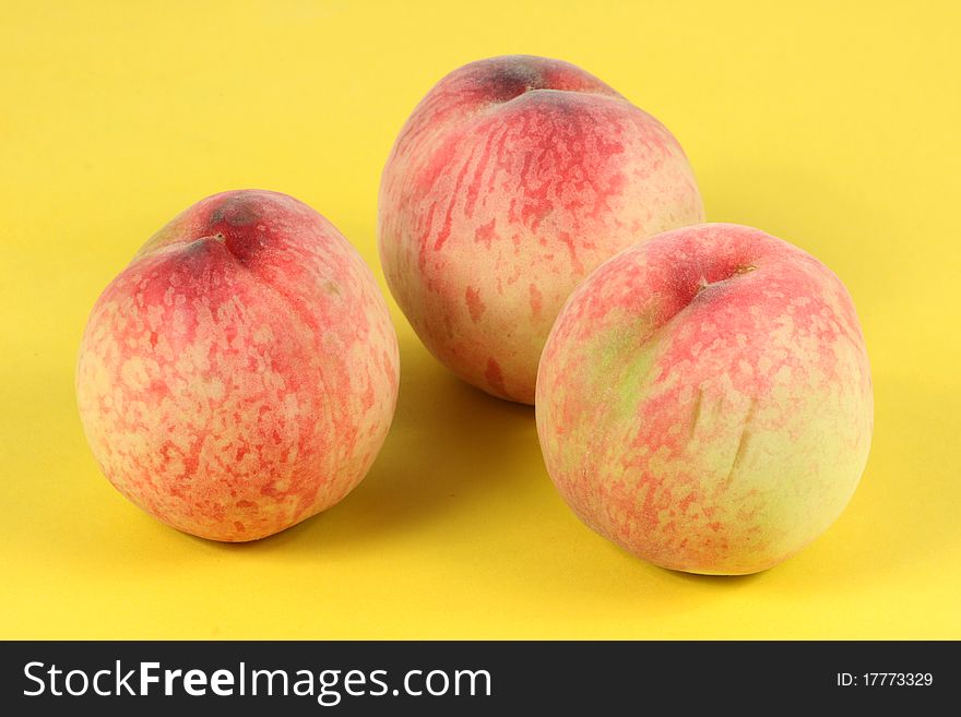 Three peaches on a yellow background