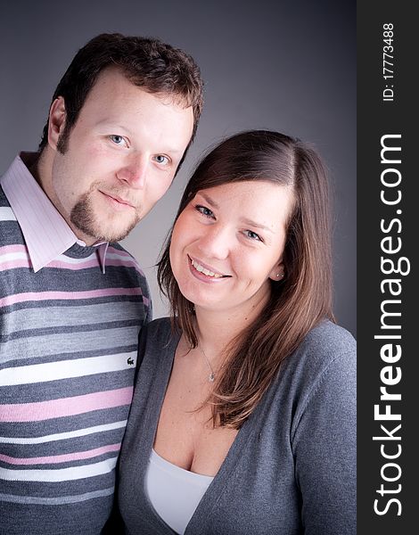 Portrait of a beautiful young couple hugging each other against grey backround