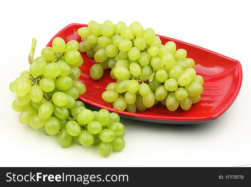 Green grapes isolated on red plate on white with clipping path.