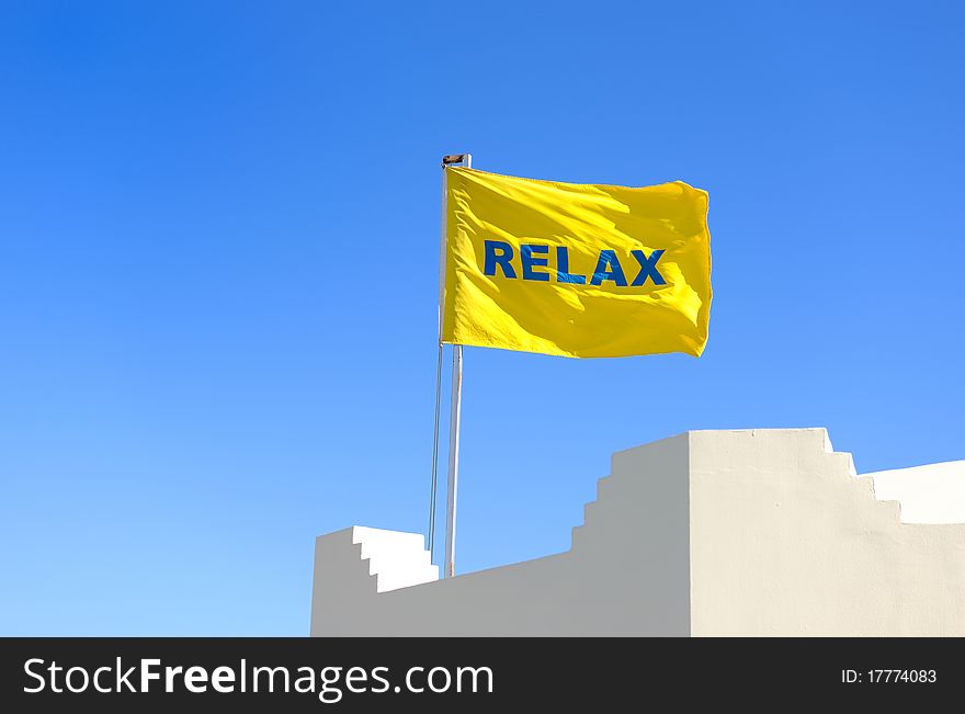 Yellow flag with a word Relax against blue sky