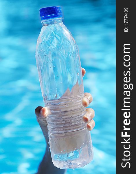 Bottle of water in a hand against water