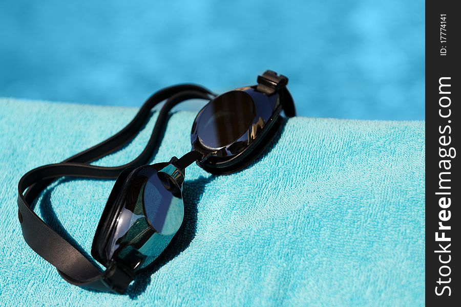 Swimming glasses on a blue towel against water