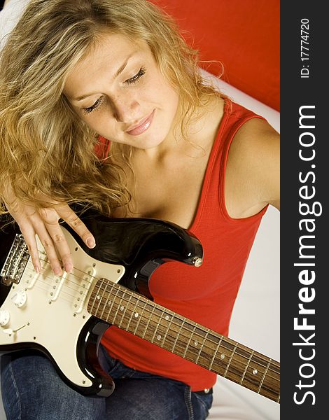 Young attractive woman with electric guitar sitting on the couch. Young attractive woman with electric guitar sitting on the couch