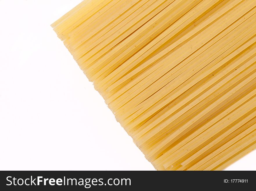 Spaghettis lie on a white background in the right part of a shot. Focus on the image middle