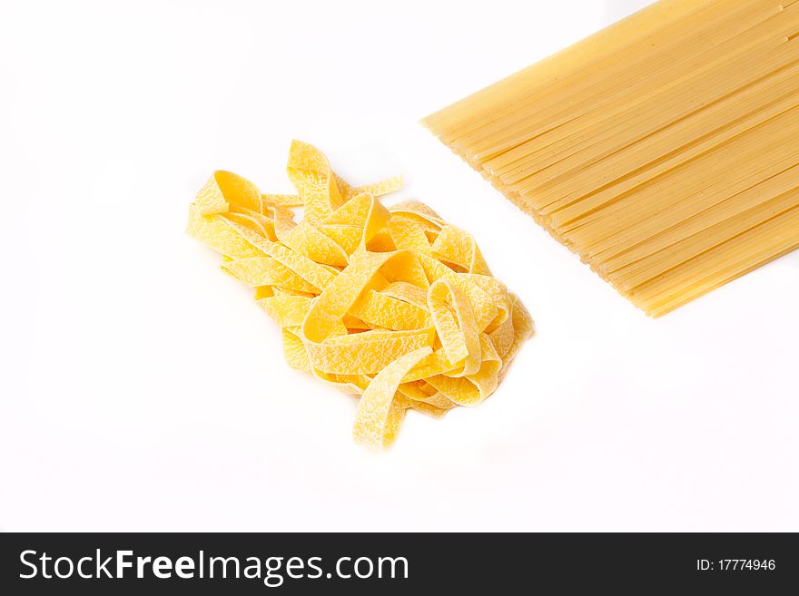 Two kinds of a spaghetti lie on a white background. Focus on the shot middle.