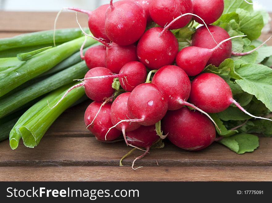 Red radishes and green onions on a wooden table. Red radishes and green onions on a wooden table
