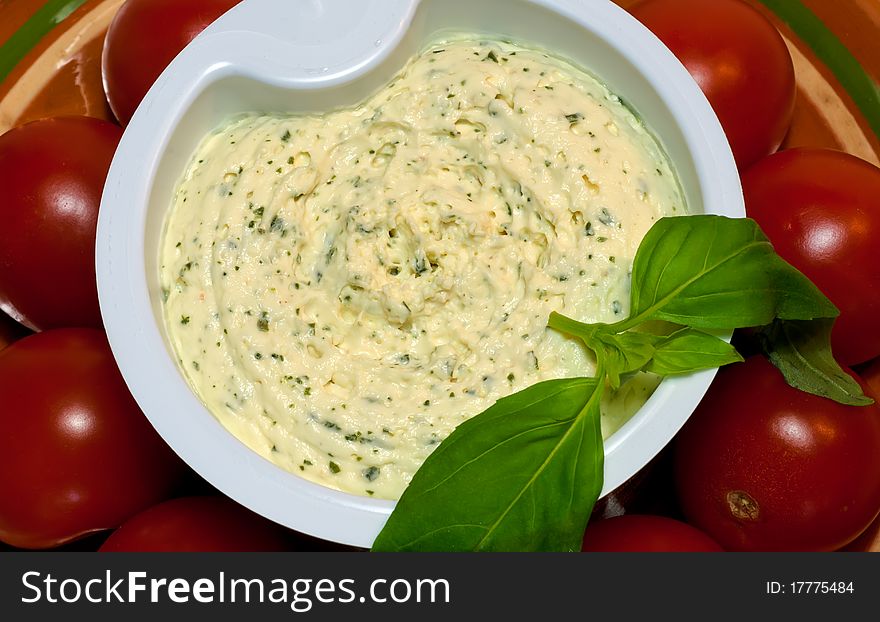 Studio shot of Cream Cheese With Garlic And Greens surrounded by cherry tomatoes