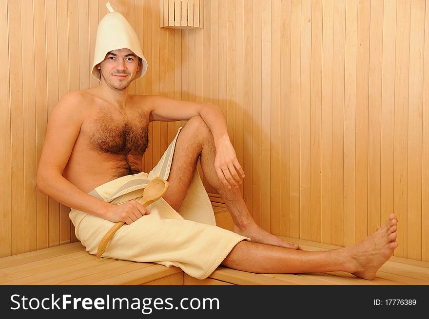 Young handsome man in a towel relaxing in a russian wooden sauna. Young handsome man in a towel relaxing in a russian wooden sauna