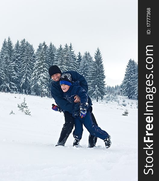 Father and his son playing in the snow on a cloudy day. Father and his son playing in the snow on a cloudy day