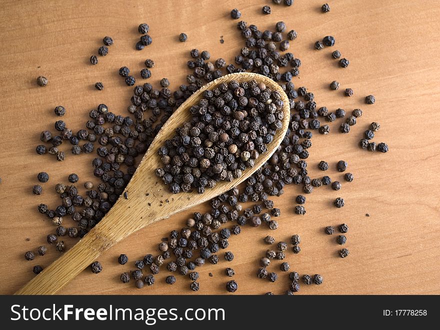 Black pepper in a wooden spoon