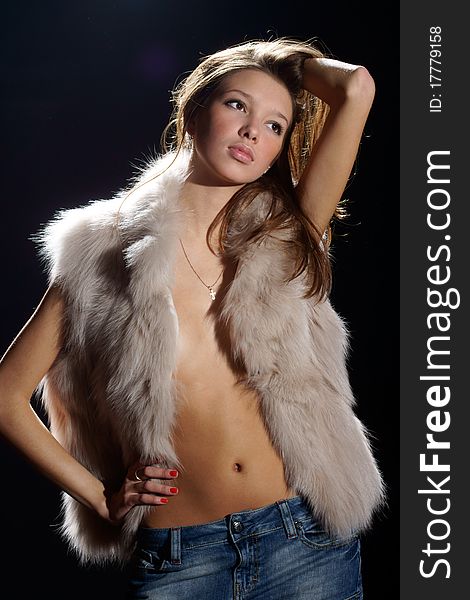 Studio photo of young pretty and woman posing in fur and jeans skirt. Studio photo of young pretty and woman posing in fur and jeans skirt