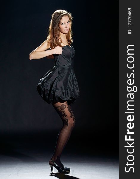 Studio fashion style photo of young attractive slim woman posing in black stylish dress. Studio fashion style photo of young attractive slim woman posing in black stylish dress