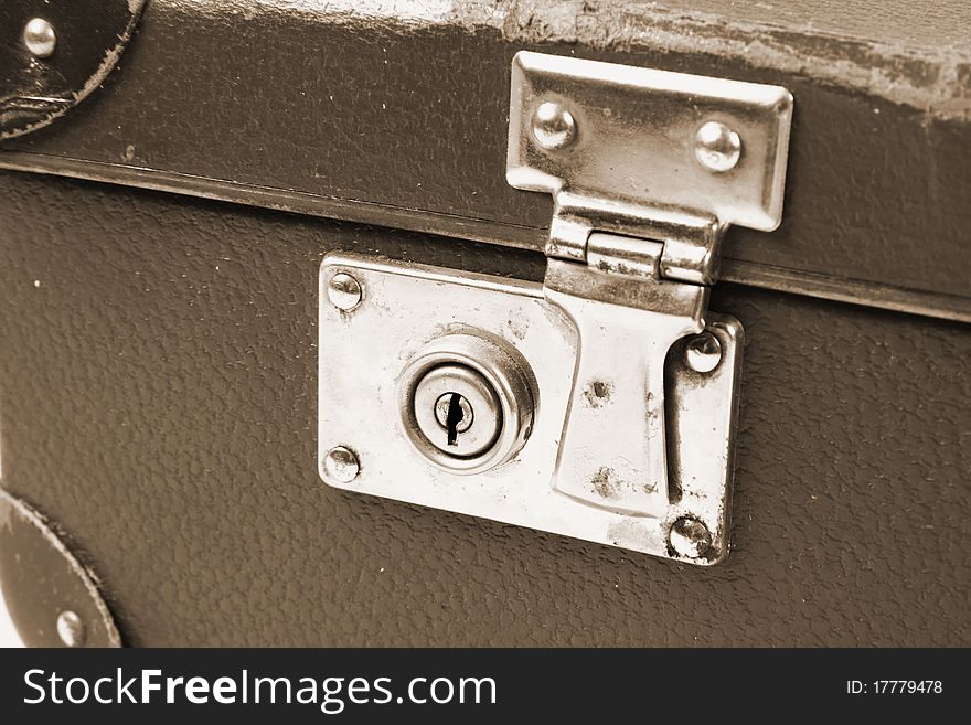 Vintage suitcase with a lock in sepia in close up