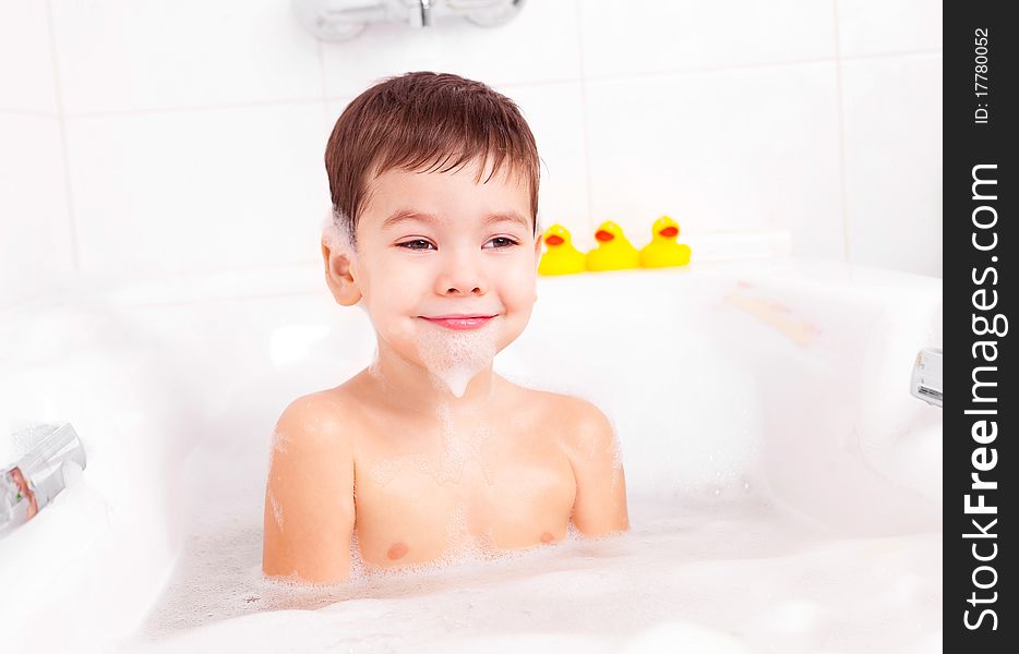 Cute four year old boy taking a relaxing bath with foam. Cute four year old boy taking a relaxing bath with foam