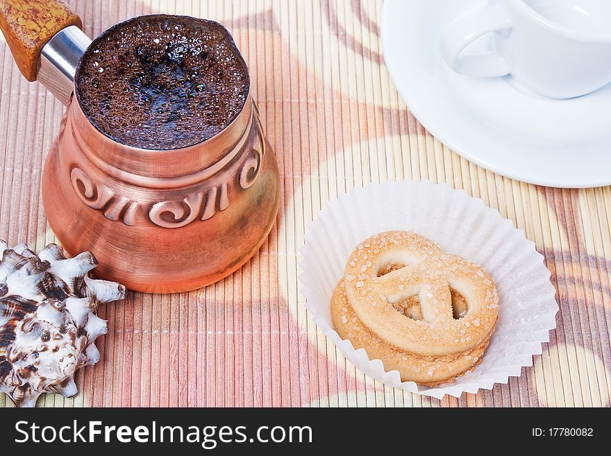 Freshly brewed hot turkish coffee in copper coffee pot with cup, cookies and seashell as decoration. Freshly brewed hot turkish coffee in copper coffee pot with cup, cookies and seashell as decoration
