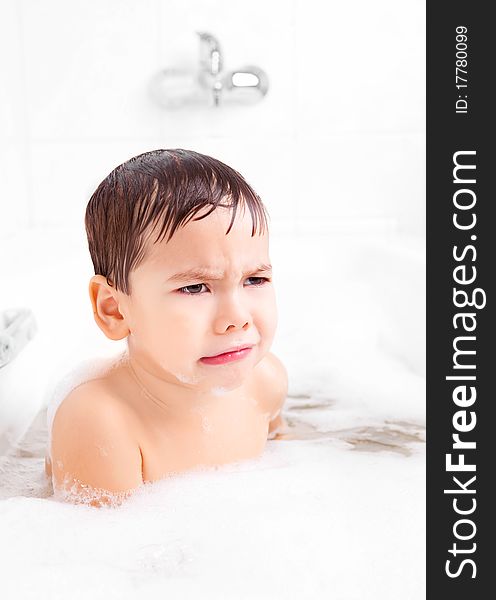Displeased unhappy four year old boy taking a bath with foam. Displeased unhappy four year old boy taking a bath with foam