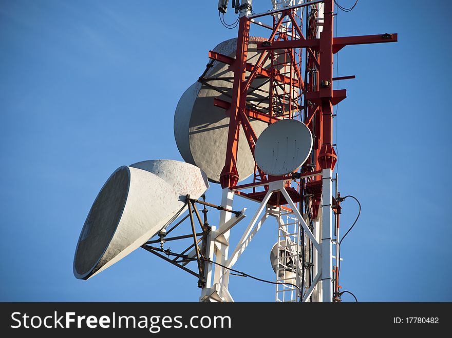 Communication antenna tower and satellite dish against blue sky. Communication antenna tower and satellite dish against blue sky