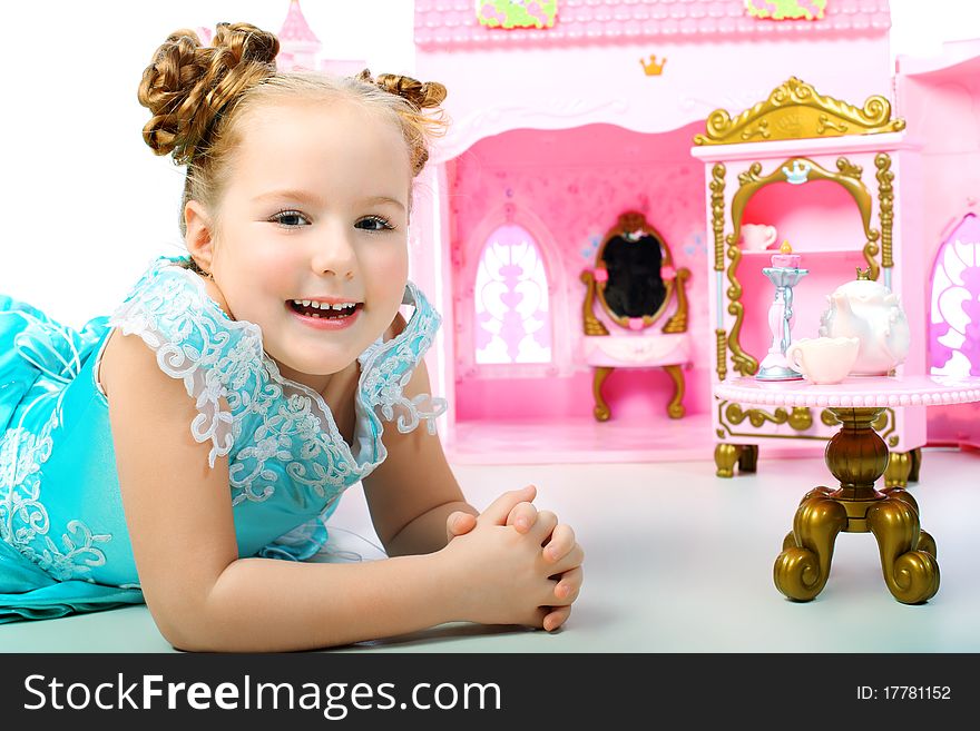 Beautiful little girl in princess dress playing with her toy castle.