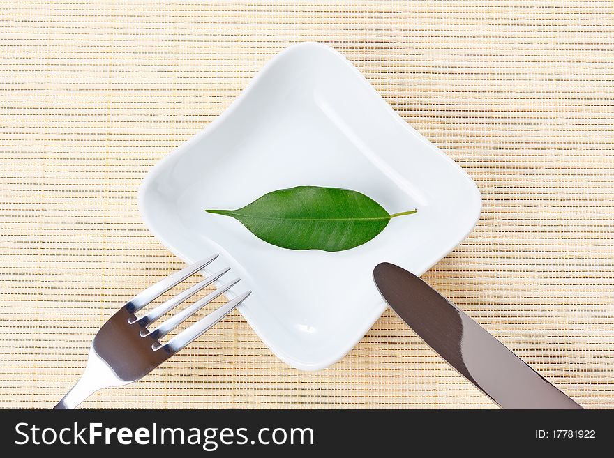 Green leaf on a plate as vegetarian diet - concept of healthy dieting