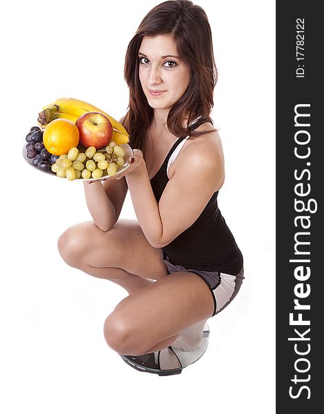 A woman is holding up a plate of fruit while smiling. She is satisfied with her weight because of her healthy diet. A woman is holding up a plate of fruit while smiling. She is satisfied with her weight because of her healthy diet.