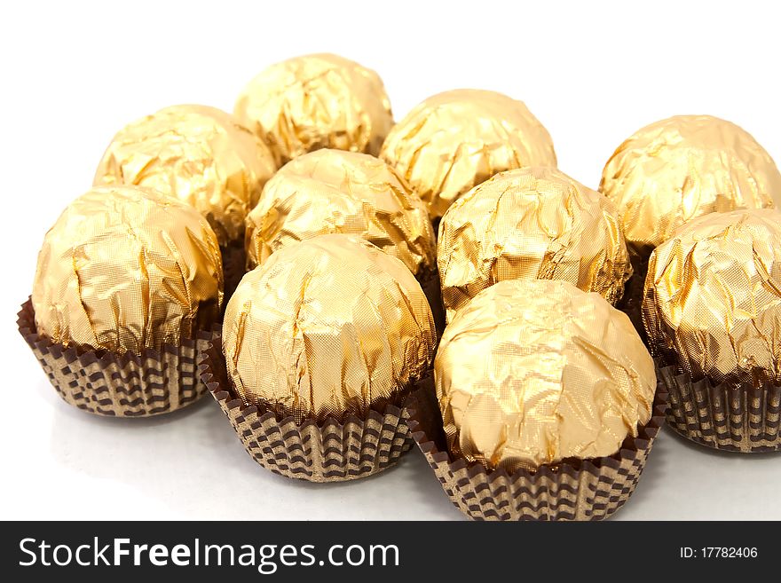 Chocolates in a gold foil papper on white background. Chocolates in a gold foil papper on white background