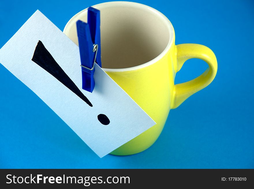 Paper with an exclamation point drawn by peg clipped on a yellow cup. Paper with an exclamation point drawn by peg clipped on a yellow cup