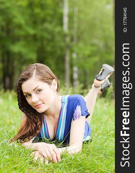 Pretty teenager lying down on green grass in blue dress. Pretty teenager lying down on green grass in blue dress