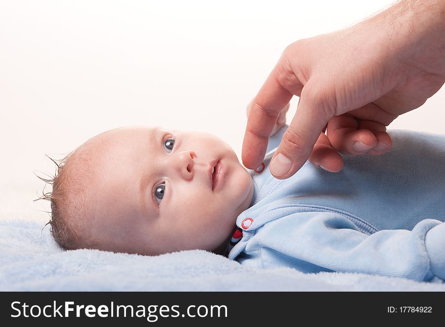 Newborn baby with fathers hand on blue towel