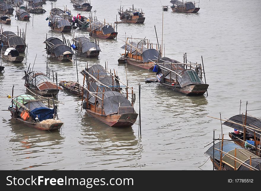 A row of wooden roofed fishing boats by the river shore, the Pearl river,Guangdhong,China. A row of wooden roofed fishing boats by the river shore, the Pearl river,Guangdhong,China.