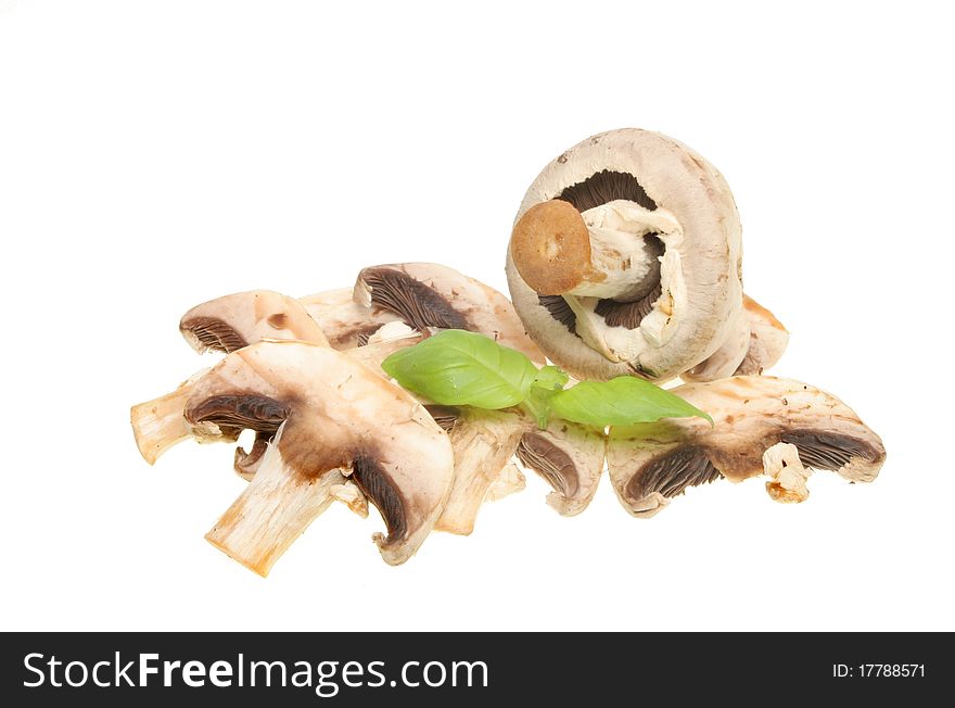 Whole and sliced closeup cap mushrooms with a sprig of basil herb isolated on white. Whole and sliced closeup cap mushrooms with a sprig of basil herb isolated on white